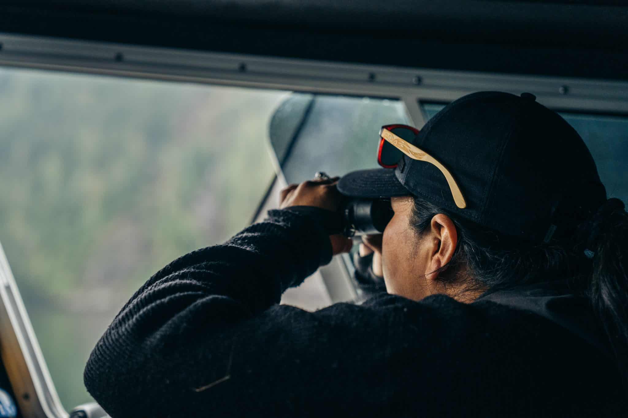 A guest on the Sea Wolf Adventures boat photographs wildlife on a misty inlet in the Great Bear Rainforest