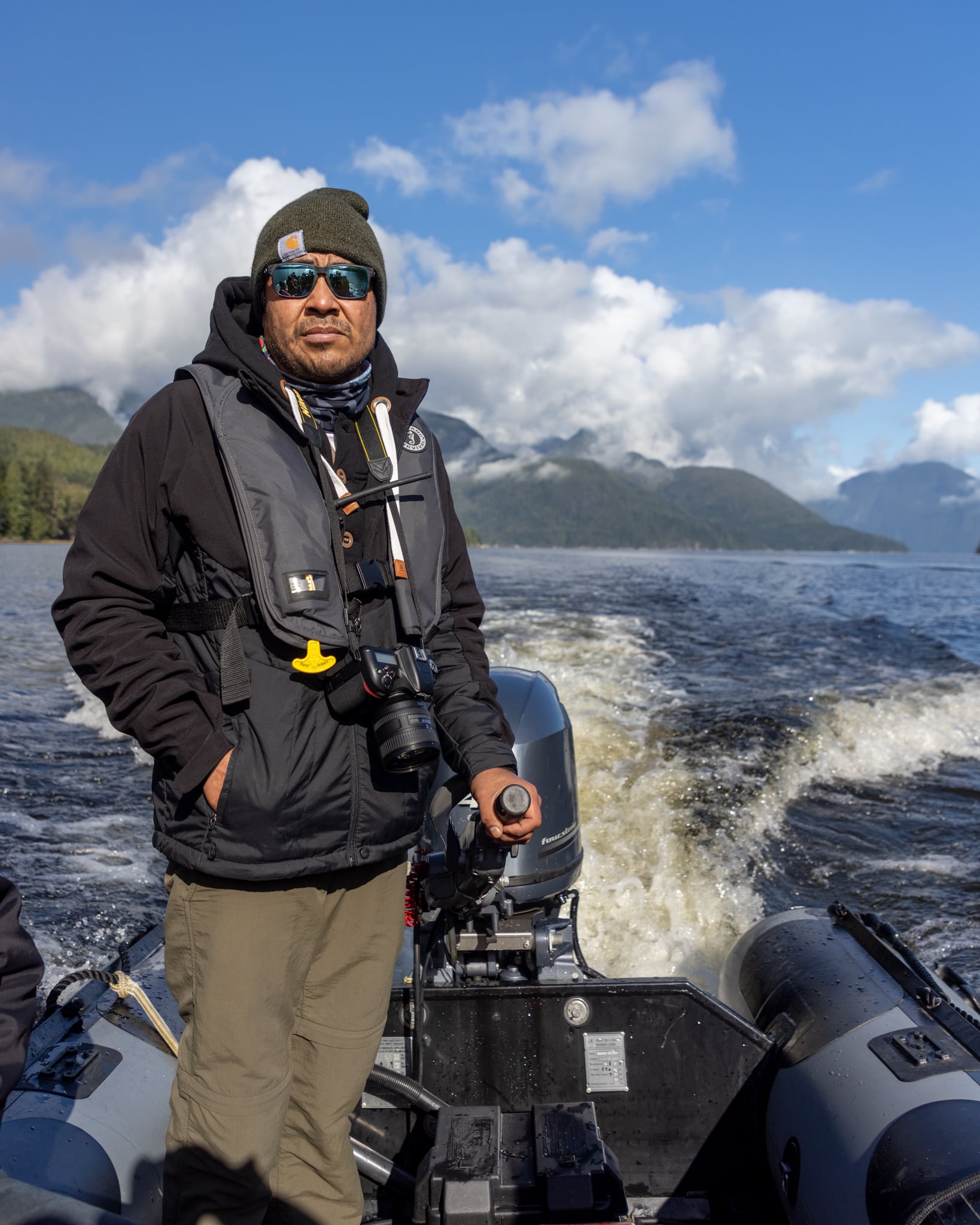 Indigenous guide steering zodiac through Knight Inlet reading the water during bear watching holiday Canada